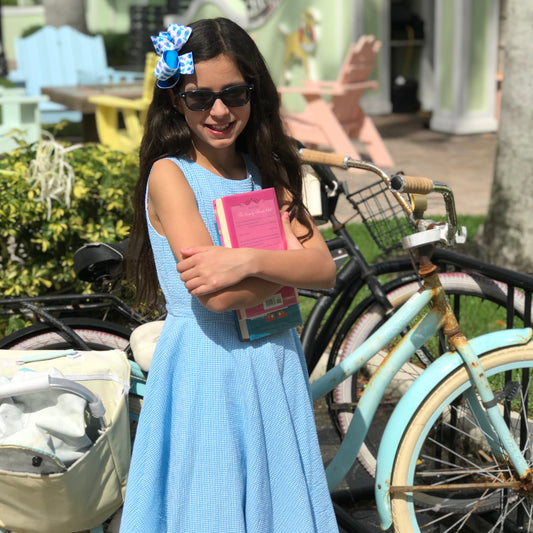 Girl holding a booking while wearing CGC's blue seersucker dress 