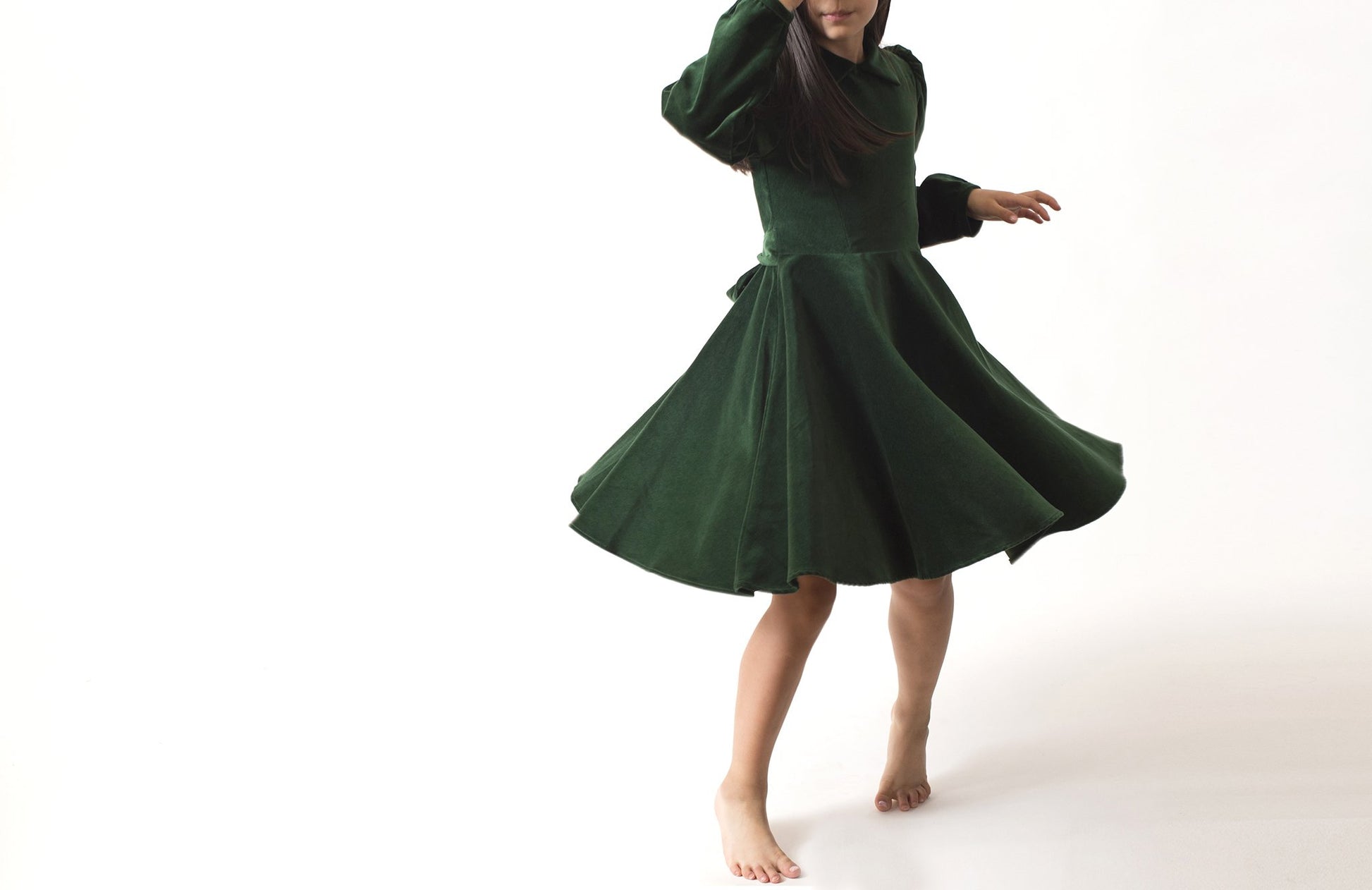 Little girl twirling in a green velvet dress.